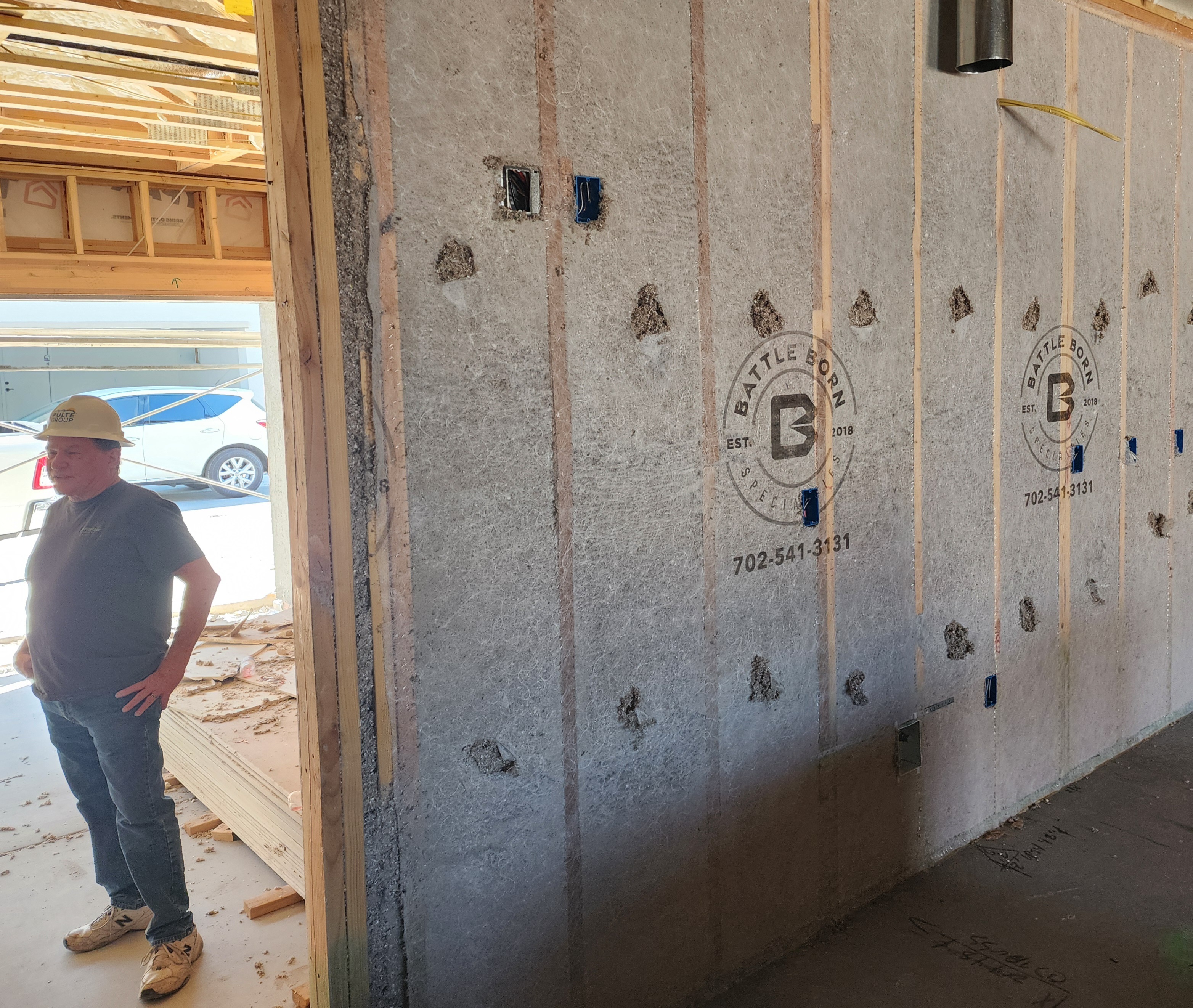 a man standing next to a wall installed with cellulose insulation